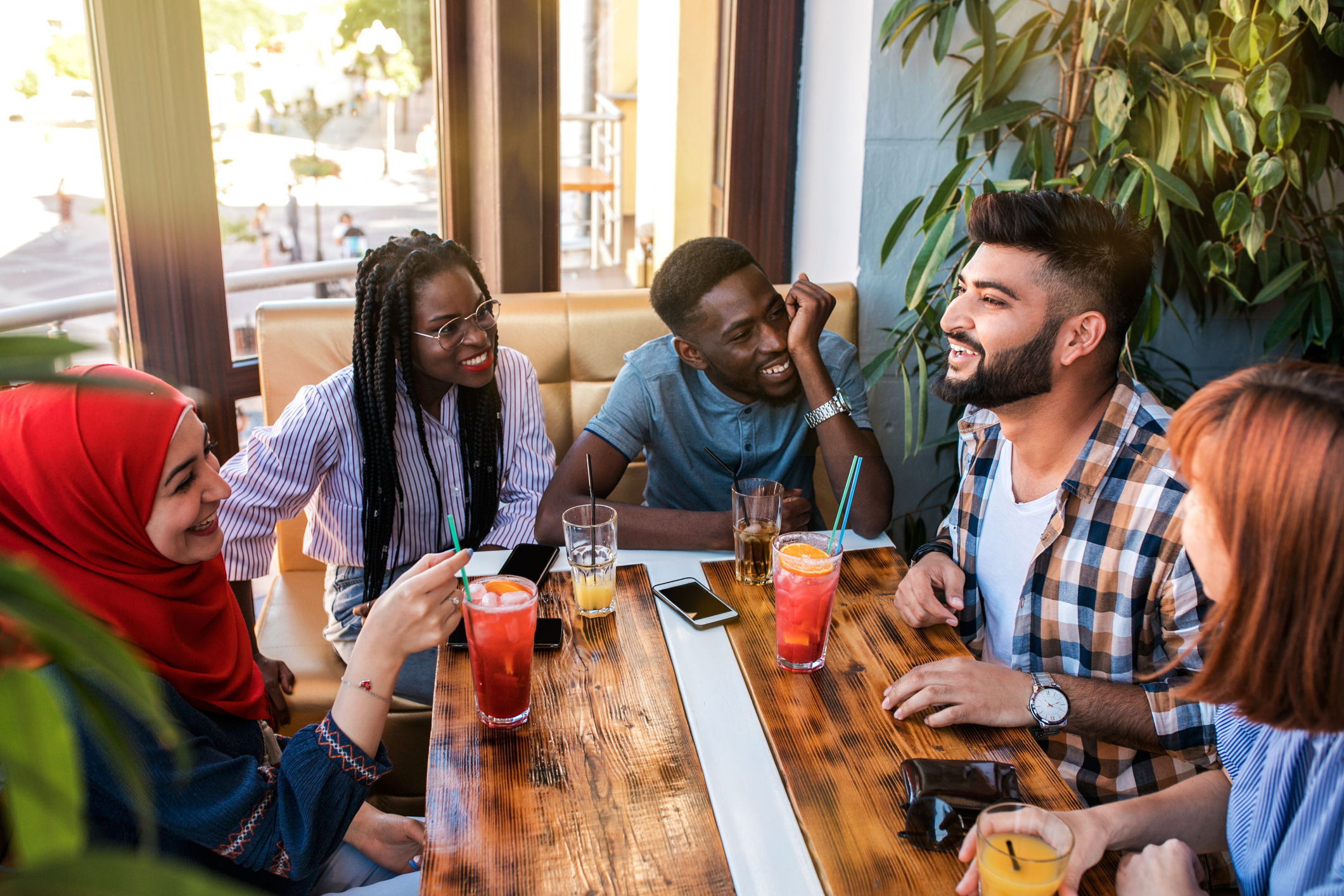 Group of happy friends drinking juice and lemonade at cafe.