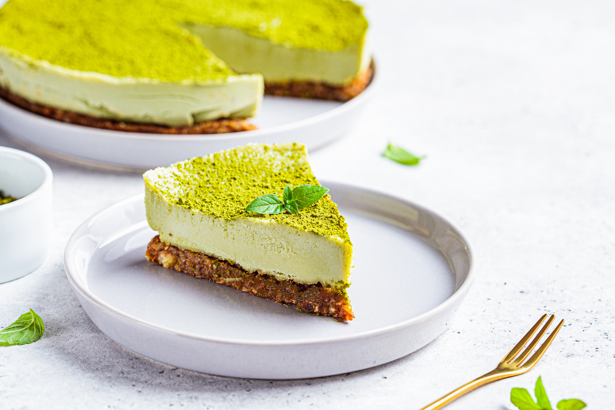 Raw vegan matcha cheesecake on a gray plate.
