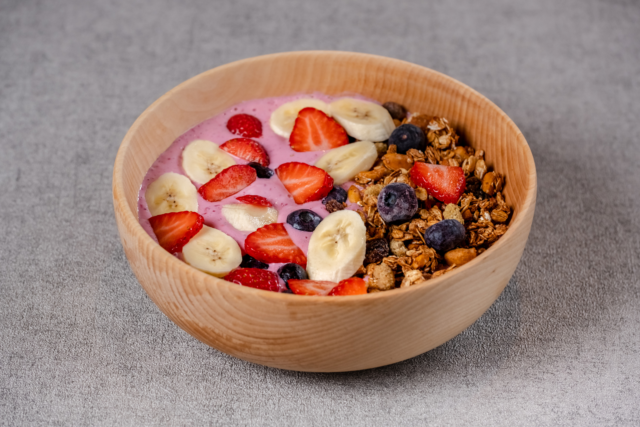 Smoothie bowl with fresh berries, bananas, strawberries, nuts, seeds and granola